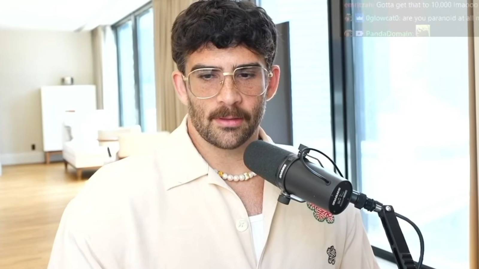 Hasan Piker speaking on stream. He is wearing white and there is a microphone in front of him